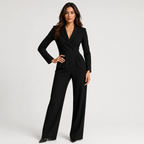 A woman modeling a black long-sleeve wrap-style jumpsuit with wide legs, photographed against a clean light gray studio background.