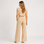 A woman shown from the back wearing a beige sleeveless top and matching wide-leg trousers, photographed against a clean light gray studio background.