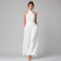 A woman modeling a white sleeveless halter-neck jumpsuit with wide legs, standing against a neutral gray studio background.