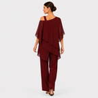 A woman modeling a burgundy two-piece outfit consisting of an off-the-shoulder draped top and matching wide-leg pants, shown from the back against a light gray studio background.