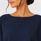 Close-up of a woman wearing a navy blue top with a wide boat neckline, shown against a light gray background.