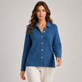 A woman modeling a blue ribbed knit button-front cardigan sweater with a collar, paired with off-white pants, against a plain light gray studio background.