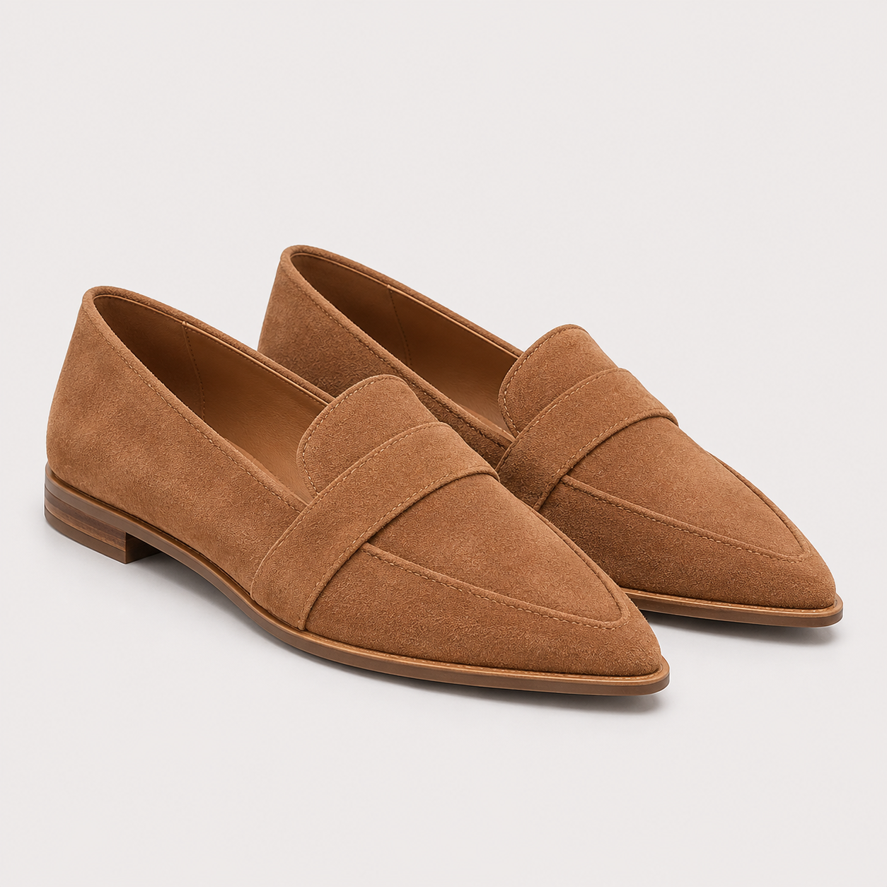 A pair of tan suede penny loafers with pointed toes, displayed on a light gray background.