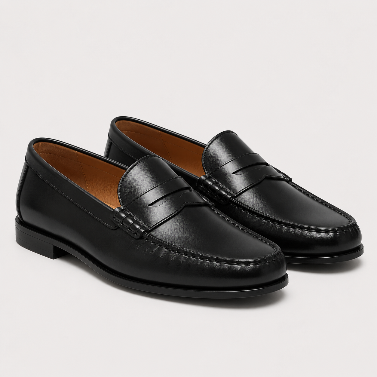 A pair of black leather penny loafers with classic stitching and a low stacked heel, displayed on a clean light gray background.
