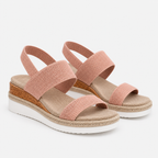 A pair of women's wedge sandals with wide, textured pink straps, a cork-look midsole, and a white outsole, shown on a light gray background.