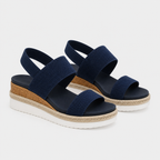 A pair of women's open-toe wedge sandals in navy blue with textured woven straps, a braided jute midsole, and a white outsole, shown on a light gray background.