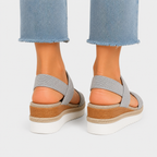 A pair of women's platform wedge sandals with light gray woven straps and a brown jute-wrapped midsole, shown on a model's feet from the back against a light gray background.