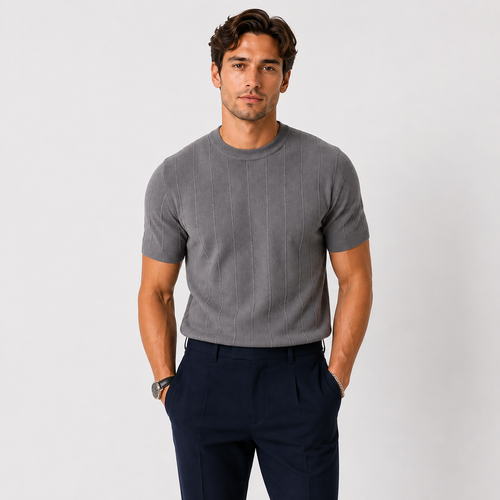 A man wearing a gray short-sleeve ribbed knit crewneck t-shirt and navy blue trousers, standing against a light gray studio background.