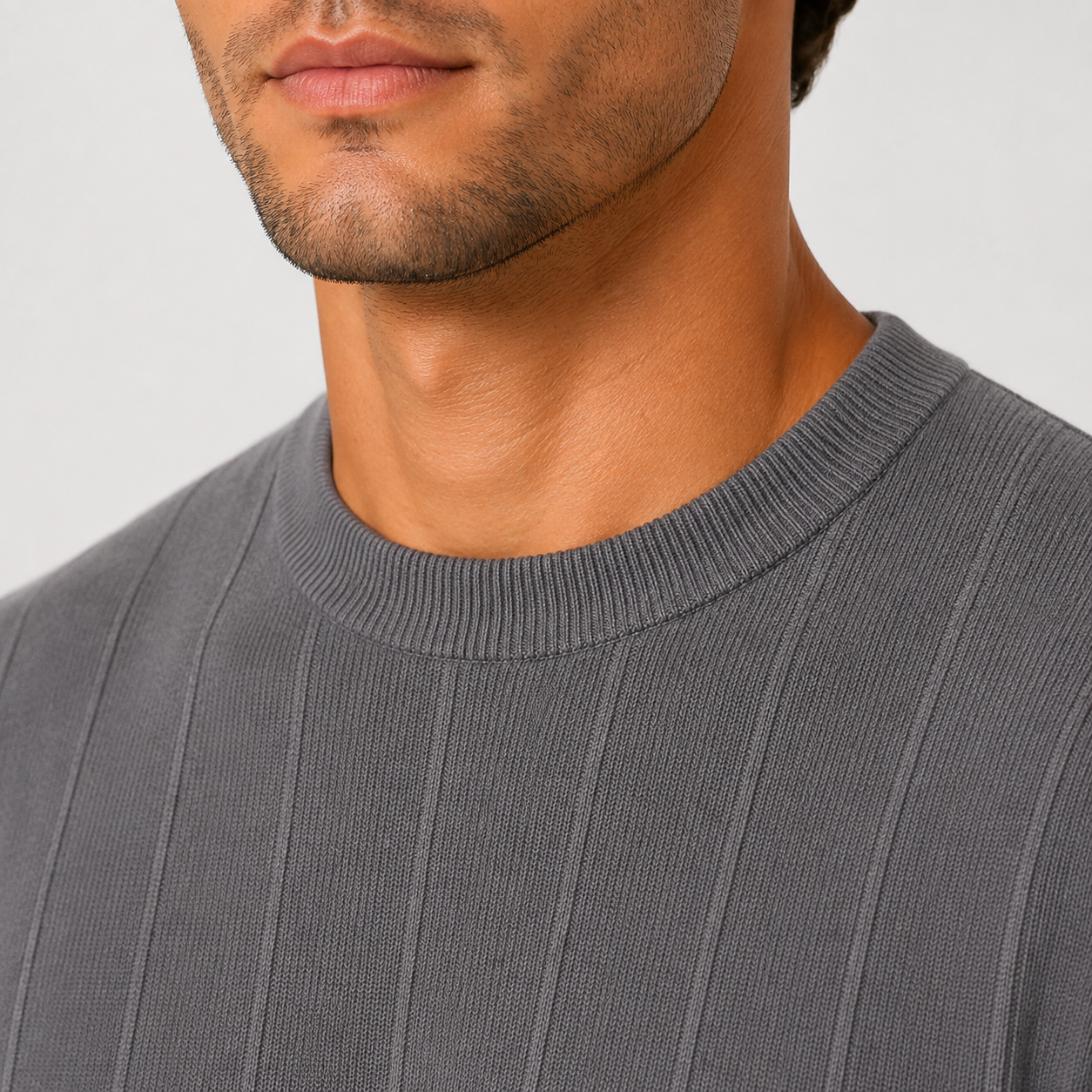 Close-up of a man wearing a dark gray ribbed crewneck sweater, showing the texture of the knit fabric and the collar.