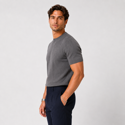 A man wearing a dark gray ribbed short-sleeve crewneck t-shirt and navy blue trousers, standing against a light gray studio background.