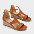 A pair of women's wedge sandals in tan leather with adjustable ankle straps and open toes, shown on a light gray background.