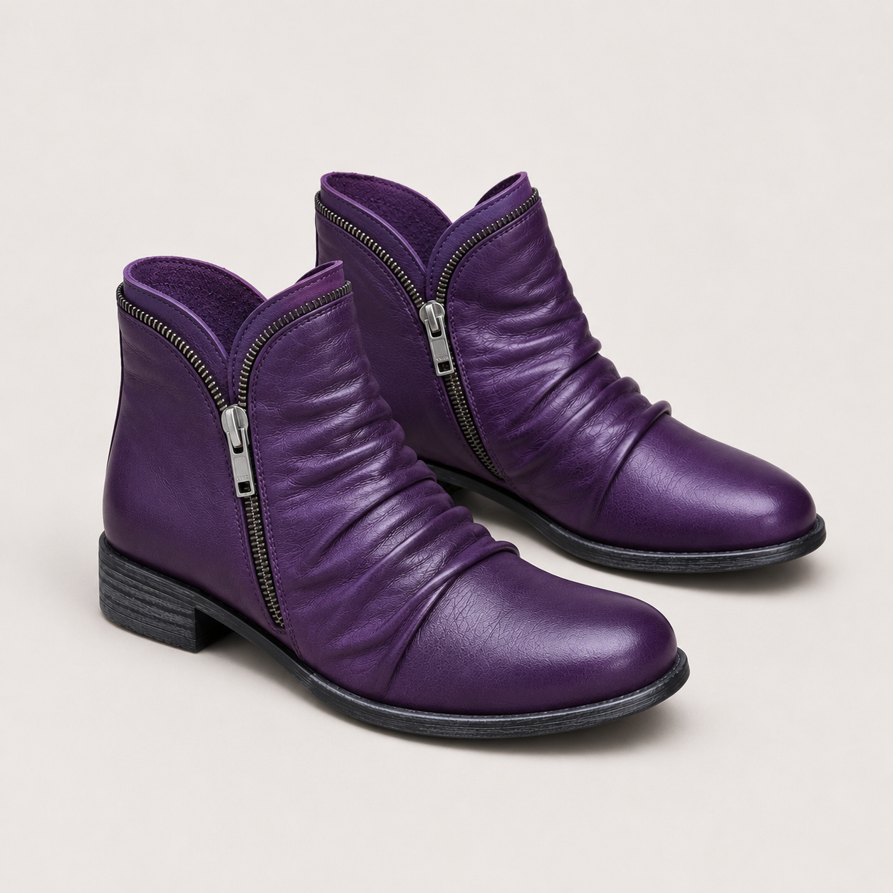 A pair of purple leather ankle boots with side zippers, shown on a light beige background.