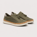 A pair of women's slip-on sneakers in olive green suede, featuring perforated side panels, matching tassel laces, a cork-wrapped midsole, and a white rubber outsole, shown against a light gray background.