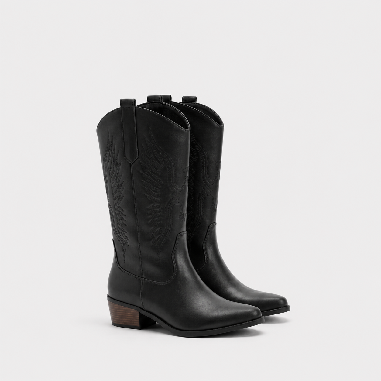 A pair of black leather cowboy boots with pointed toes and low stacked heels, shown from a side profile against a light gray background.
