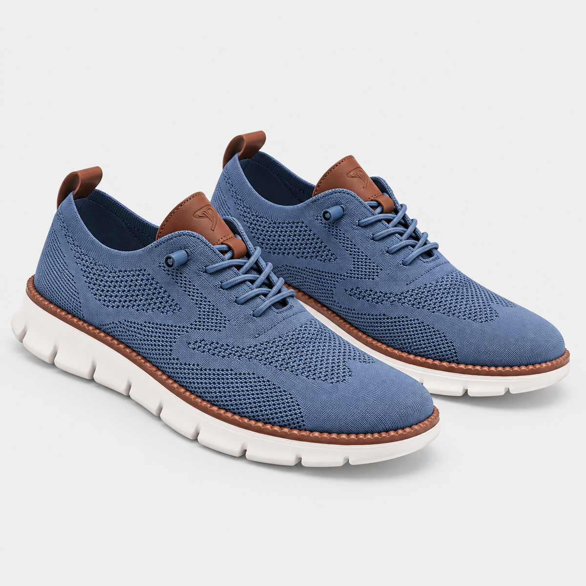 A pair of blue knit lace-up sneakers with brown leather trim and pull tabs, featuring a white flexible sole, shown on a light gray background.