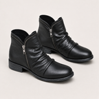 A pair of black leather ankle boots with a side zipper, low block heel, and rounded toe, shown on a light beige background.