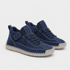A pair of mid-top sneakers in navy blue suede and canvas with light beige soles, shown on a light gray background.