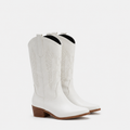 A pair of white leather cowboy boots with western embroidery and low brown block heels, shown against a plain light gray background.