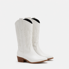 A pair of white leather cowboy boots with western embroidery and low brown block heels, shown against a plain light gray background.