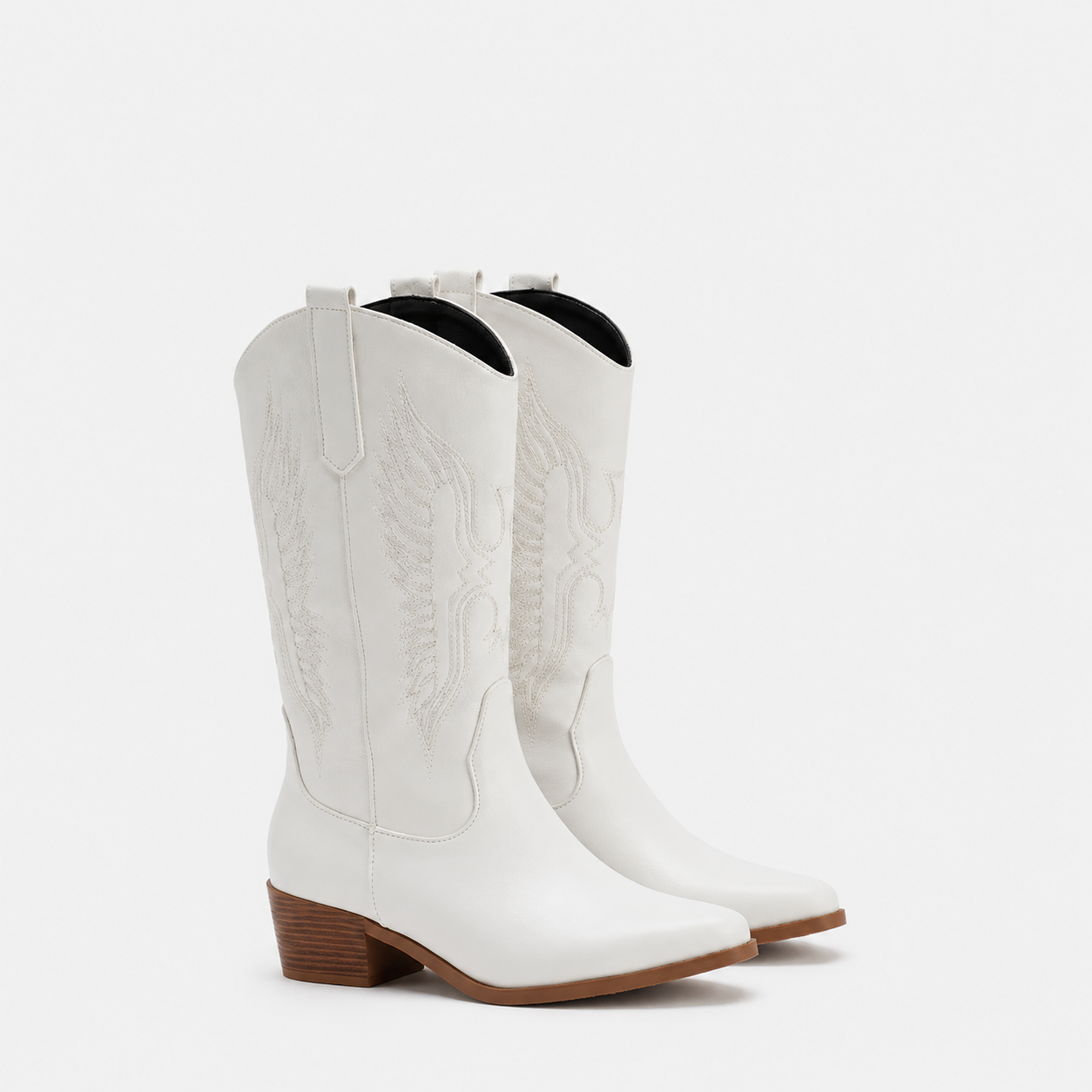 A pair of white leather cowboy boots with western embroidery and low brown block heels, shown against a plain light gray background.