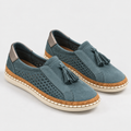 A pair of women's slip-on espadrille-style shoes in muted blue suede with perforated side panels, tassel details, cork-wrapped midsoles, and off-white soles, photographed on a light gray studio background.