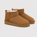 A pair of toddler ankle boots in tan suede with a white shearling lining, shown on a light gray background.