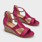 A pair of women's wedge sandals in a vibrant magenta pink, featuring open toe straps, side zippers, and tan wedge heels, shown on a light gray background.