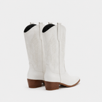 A pair of white leather cowboy boots with embossed western stitching and stacked brown block heels, shown from a rear three-quarter angle on a light gray background.