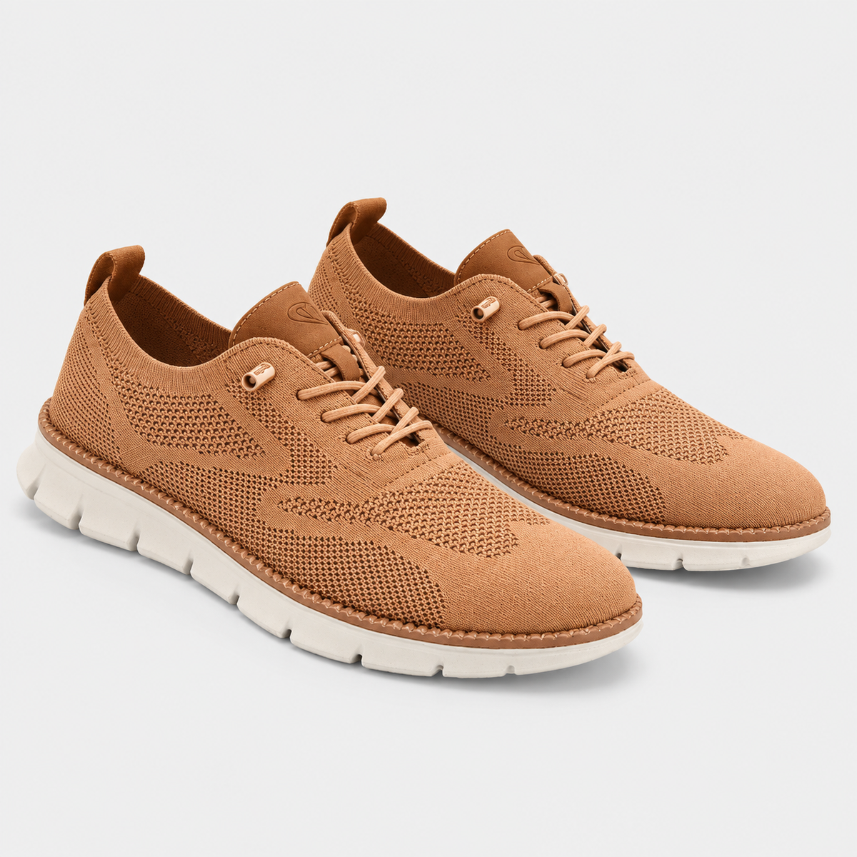 A pair of casual lace-up sneakers in a warm tan color, featuring a textured knit and suede upper with a thick white sole, shown on a light gray background.