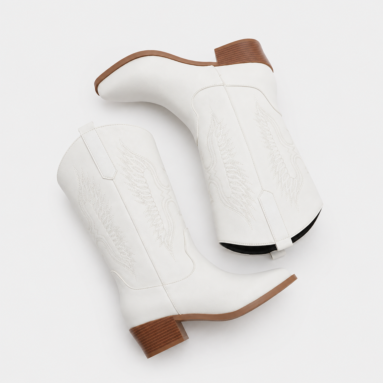 A pair of white leather western boots with tan stacked heels and toes, featuring white embroidered stitching on the shafts, shown on a light gray background.