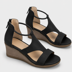 A pair of women's black wedge sandals with cutout straps, ankle ties, and side zippers, shown on a light gray background.