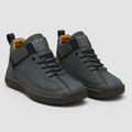 A pair of mid-top athletic sneakers in slate blue with dark brown stitching, black laces, and a yellow interior lining, shown on a light gray background.