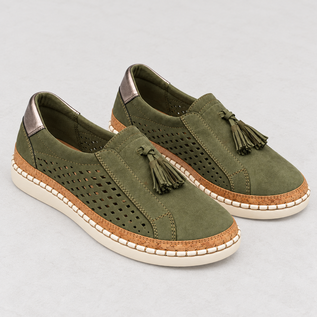 A pair of women's slip-on espadrille-style shoes in olive green suede, featuring perforated side panels, tassel details, a tan cork-look midsole, and off-white soles, shown on a light gray background.