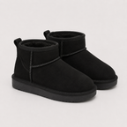 A pair of black suede ankle boots with black faux-fur lining and black soles, photographed on a clean, light gray background.