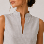 Close-up of a woman wearing a sleeveless top with a high stand collar and a split V-neckline, featuring fine vertical stripes in light gray and white.
