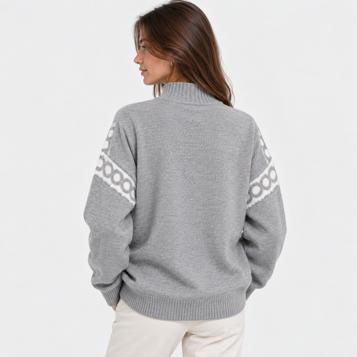 A woman shown from the back wearing a heather gray knit sweater with a white geometric pattern along the shoulders and sleeves, paired with off-white pants, against a plain white studio background.