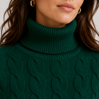 Close-up of a woman wearing a dark green ribbed turtleneck sweater with a cable-knit pattern, featuring gold hoop earrings.