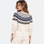 A woman shown from the back wearing a cream knit sweater with a multicolor geometric Fair Isle yoke pattern in navy, blue, white, and brown, paired with cream pants against a plain white studio background.