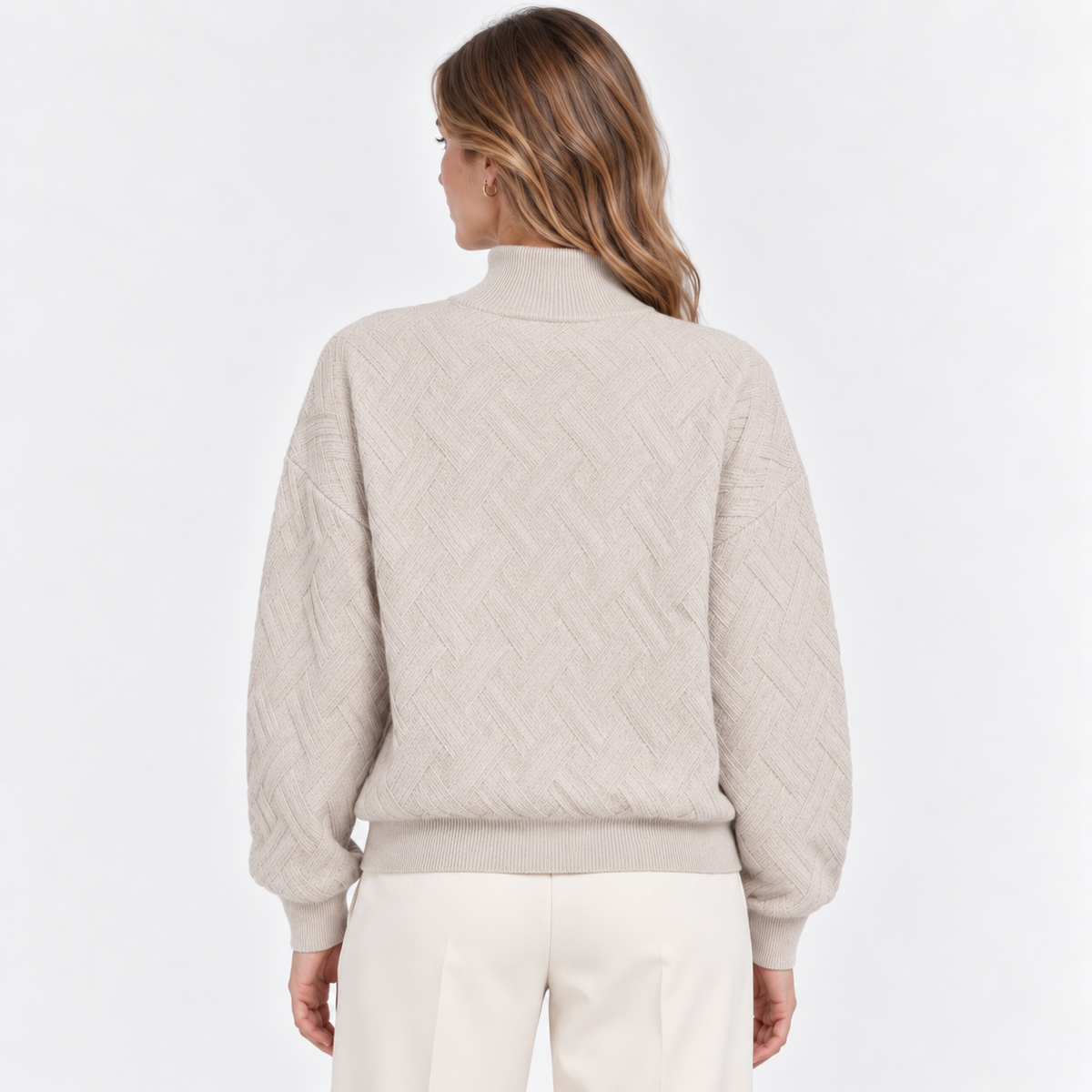 A woman shown from the back wearing a light beige textured knit sweater and cream pants against a clean white studio background.
