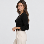 A woman modeling a black ribbed knit long-sleeve sweater with a V-neck, paired with cream trousers, against a plain light gray studio background.