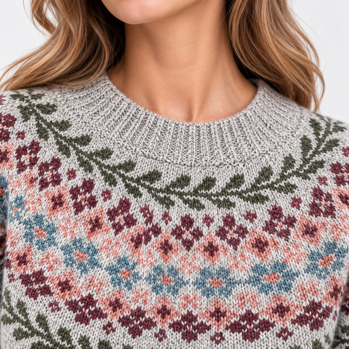 Close-up of a woman wearing a knitted crewneck sweater with a Fair Isle pattern in gray, dusty pink, blue, burgundy, and olive green.