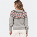 A woman shown from the back wearing a light gray knit sweater with a multicolor Fair Isle pattern across the shoulders and upper back, paired with cream pants, against a plain white studio background.