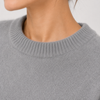 Close-up of a person wearing a light gray ribbed knit crewneck sweater, showing the neck and upper chest against a plain light background.