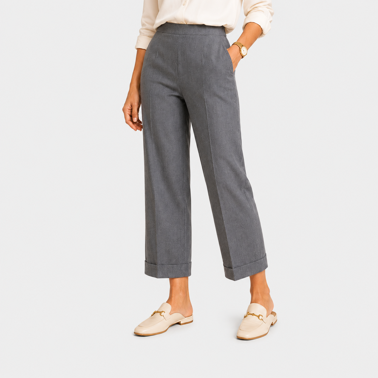 A model wearing gray cropped wide-leg trousers with rolled cuffs, paired with a cream blouse and beige loafers, shown against a light gray studio background.