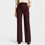 A model is shown from the waist down wearing a pair of high-waisted, wide-leg trousers in a deep burgundy color, paired with a light beige blouse and dark burgundy heels, against a light gray studio background.
