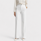 A model wearing high-waisted white wide-leg trousers, paired with a cream satin blouse and white pointed-toe heels, against a light gray studio background.
