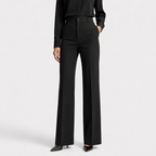 A model wearing black wide-leg trousers with a high waist, paired with a black long-sleeve top and black pointed-toe heels, shown against a light gray studio background.