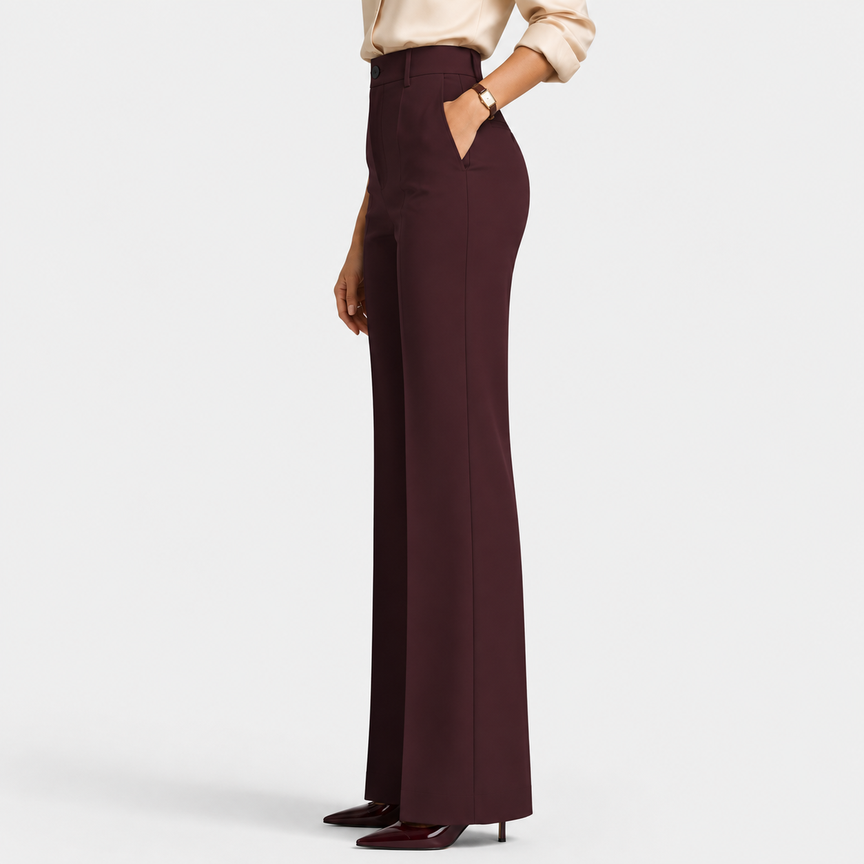 A model is shown from the waist down wearing high-waisted, wide-leg trousers in a deep burgundy color, paired with a light beige blouse and dark burgundy heels, against a plain light gray studio background.