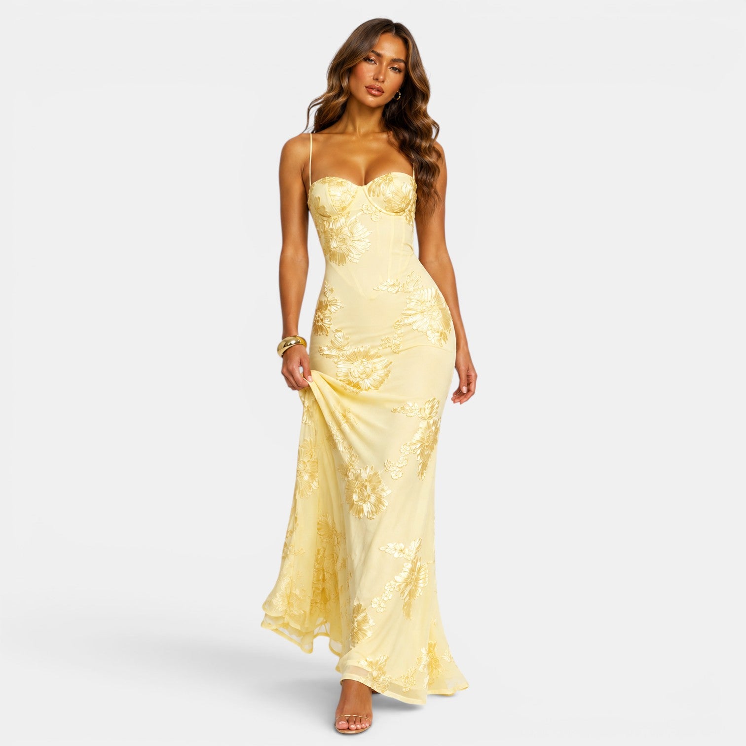 Woman wearing a yellow strapless gown with sequin details on a white background