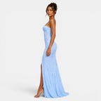 Woman wearing a light blue strapless gown with a slit on a white background